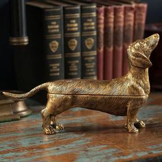 a golden dachshund dog figurine sitting on a desk next to books