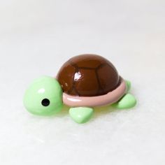 a small toy turtle sitting on top of a white table next to a brown and pink object