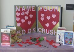 a table topped with books and teddy bears next to two valentine's day signs