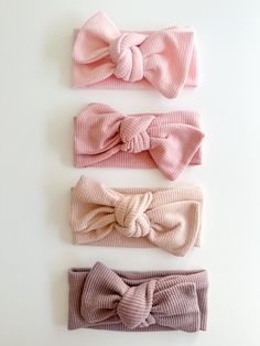 three bow headbands in different colors on a white surface with one pink, the other grey