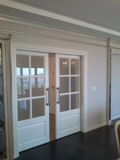 an empty living room with two doors and chairs in front of the sliding glass door