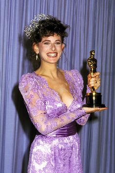 a woman in a purple dress holding an award for her role in the television show