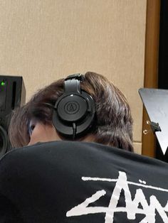 a man with headphones on sitting in front of a microphone and sound equipment behind him