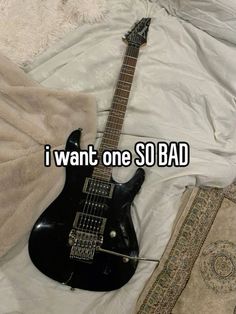 an electric guitar laying on top of a bed next to a blanket and rug with the caption i want one so bad