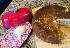 a cake sitting on top of a wooden cutting board next to a red oven mitt