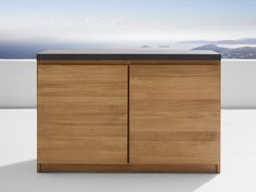 a wooden cabinet sitting on top of a white floor next to a wall and ocean