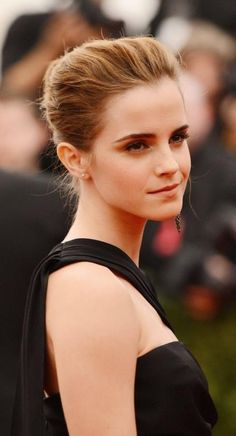 a woman in a black dress posing for the camera with her hair pulled back into a pony tail