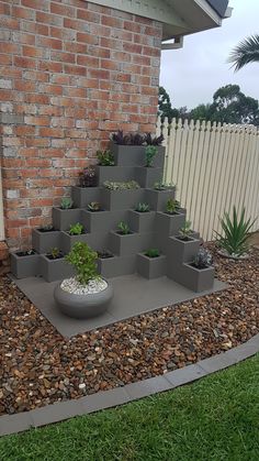 there is a planter made out of cinder blocks on the ground in front of a house