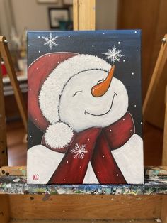 a painting of a snowman wearing a santa hat and scarf on a easel