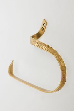 a close up of a gold bracelet on a white surface with an arrow shaped object in the middle