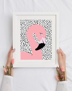 two hands holding up a pink and black print with a flamingo in the middle