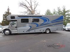 a silver and blue motor home parked in a parking lot