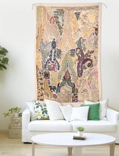 a living room with a couch, coffee table and large tapestry hanging on the wall