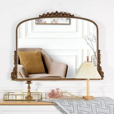 a mirror sitting on top of a table next to a lamp and a chair in front of it