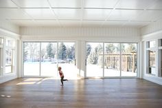 a young child is running in the middle of an empty room with sliding glass doors