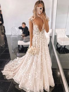 a woman taking a selfie in front of a mirror wearing a white wedding dress