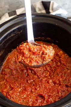 a spoon full of sauce in a slow cooker