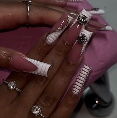 a woman's hand with pink and white nail polish on it, holding onto her manicured nails