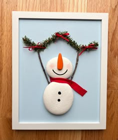 a snowman made out of rocks on top of a wooden floor next to a blue wall