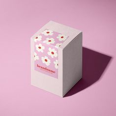 a white box with red and white flowers on it sitting on top of a pink surface