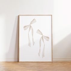 a white framed artwork hanging on the wall next to a wooden floor