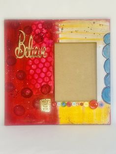 an altered picture frame with the word believe in gold and red on it's edges