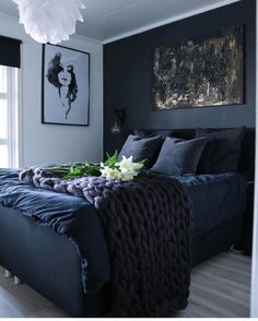 a bedroom with black walls and blue bedspread, white flowers on the bed