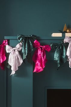 several different colored bows hanging from a shelf in front of a blue wall and fireplace