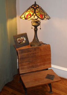 a lamp sitting on top of a wooden table next to a framed photo and an old book