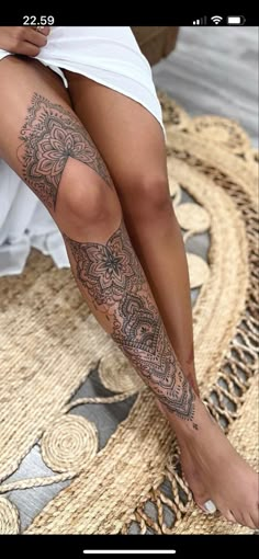 a woman is sitting on the floor with her legs crossed and tattoos on her leg