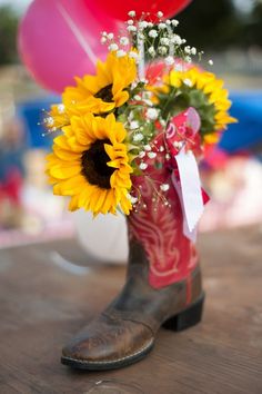 a cowboy boot with sunflowers and baby's breath in it