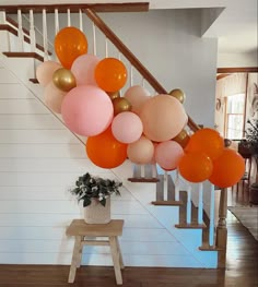 a bunch of balloons hanging from the side of a stair case next to a potted plant