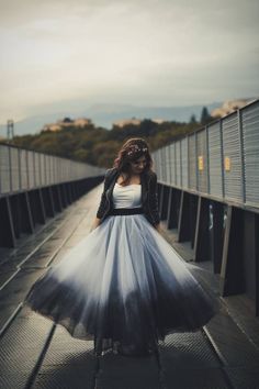 a woman is standing on a bridge wearing a dress