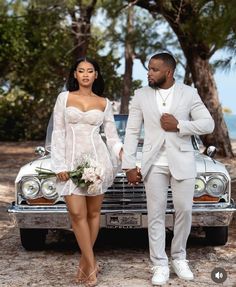 a man and woman standing in front of a car