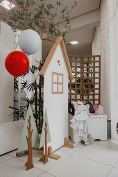 a house made out of cardboard with balloons in the air and other decorations on the floor