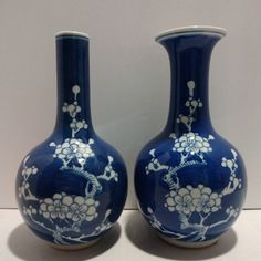 two blue and white vases sitting on top of a table next to each other