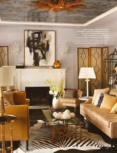 a living room filled with lots of furniture and paintings on the wall above it's fireplace