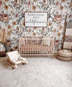 a baby's room with floral wallpaper and a crib in the foreground