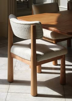 a wooden table with two chairs next to it and a light shining through the window