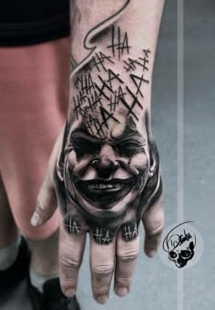 a person with a tattoo on their hand that has a clown face and words all over it