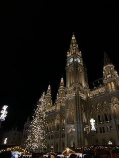 a large building with christmas lights on it's sides and a clock at the top