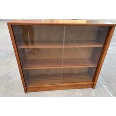 a wooden bookcase with glass doors on the front and bottom shelves in different sizes