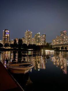 a boat is docked on the water in front of a city at night