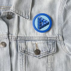 a blue and white button on the back of a jean jacket that has an image of a cube in it