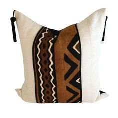 a white pillow with black and brown designs on it's side, sitting against a white background