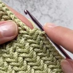 a woman is knitting with her fingers and crochet hook