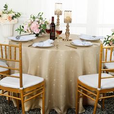 the table is set with white linens and gold chairs for two people to sit at