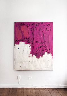 a pink and white painting hanging on the wall in an empty room with wooden floors