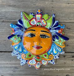 a ceramic sun face hanging on a wooden wall in the shape of a woman's face