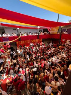 a large group of people standing in front of a red and yellow tent at an event